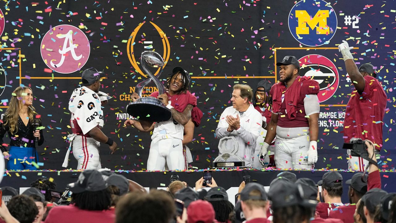 Alabama's Jameson Williams holds up the winner's trophy as coach Nick Saban watches.