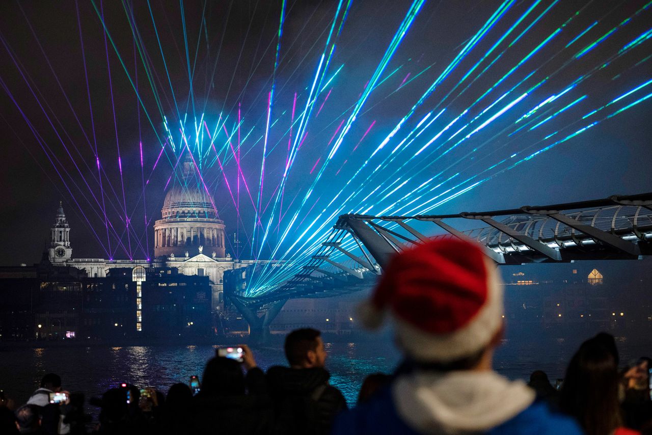 People watch the light show by St. Paul's Cathedral and the Millennium Bridge in London.