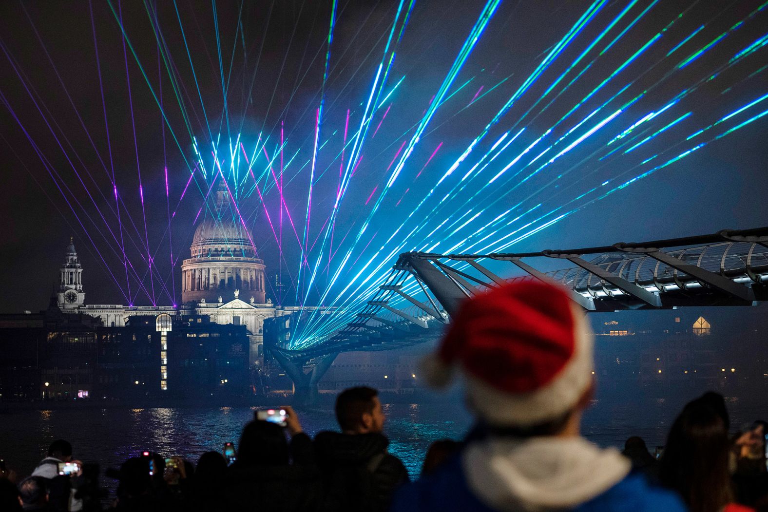 People watch the light show by St. Paul's Cathedral and the Millennium Bridge in London.