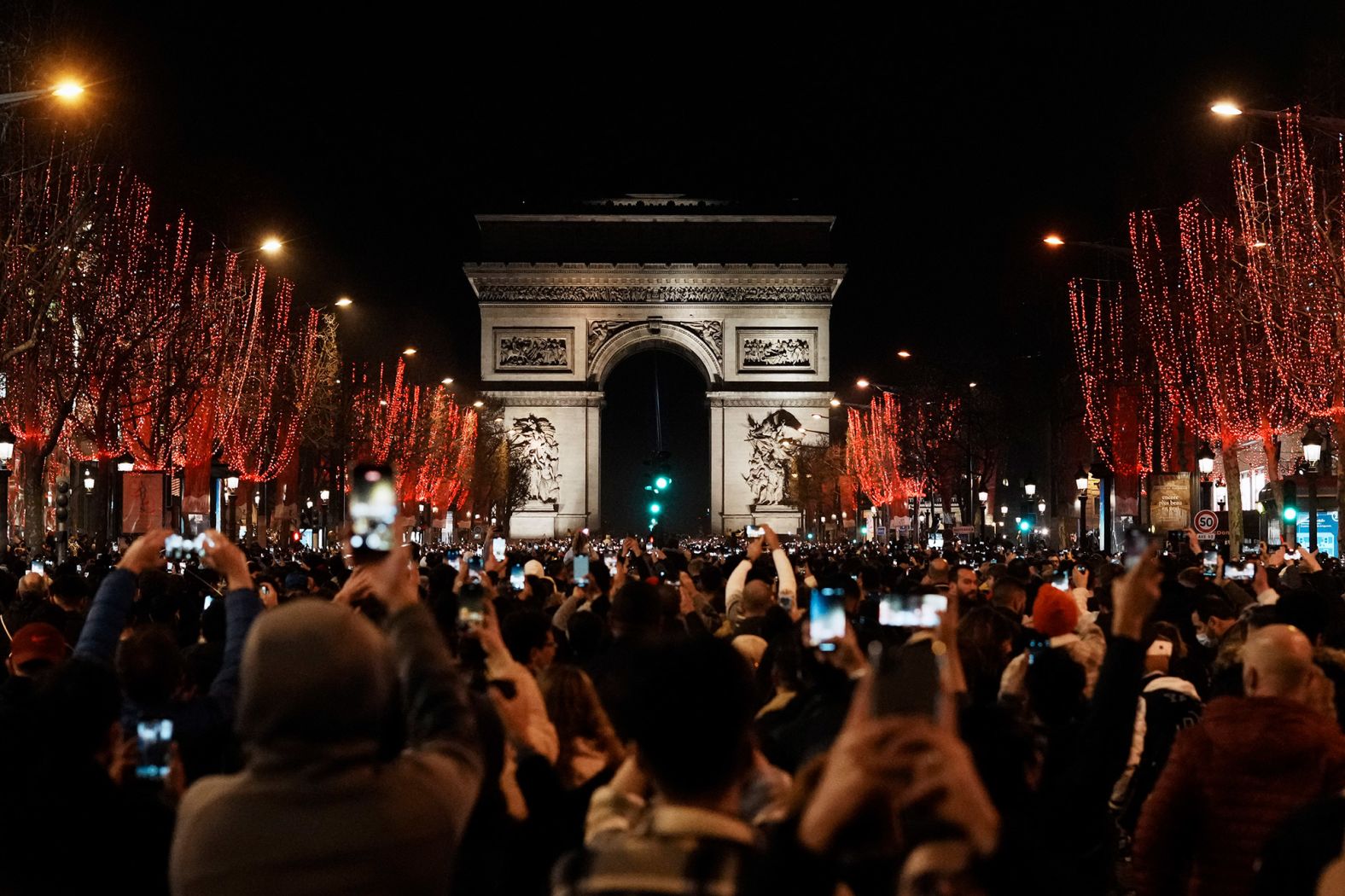 People celebrate on the Champs-Elysées Avenue in Paris. The city canceled its traditional fireworks display.