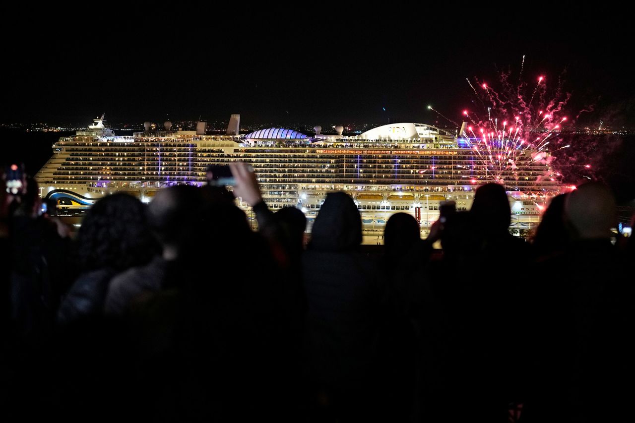 People in Lisbon, Portugal, take pictures of fireworks in front of the docked German cruise ship AIDAnova.