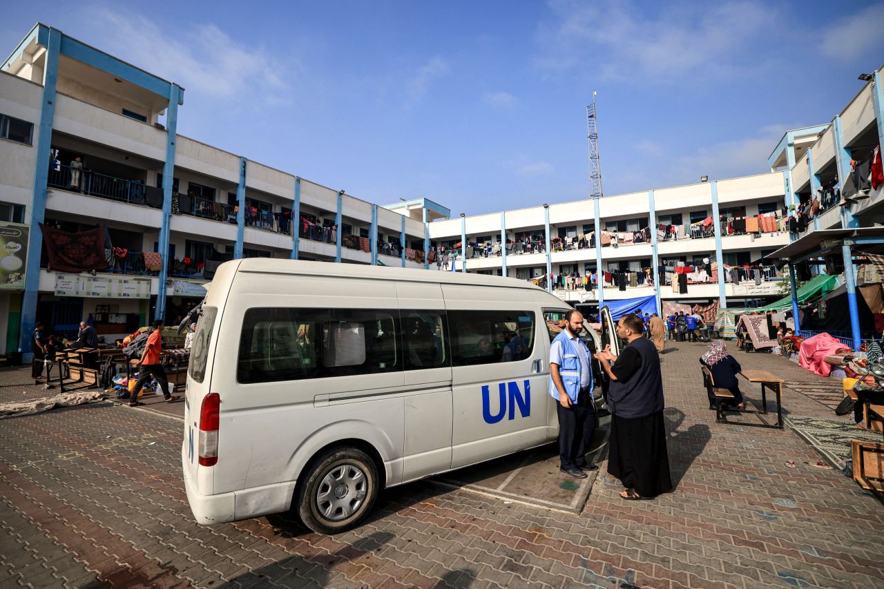 A man speaks with a worker of the United Nations Relief and Works Agency for Palestine Refugees (UNRWA) agency outside one of their vehicles parked in the playground of an UNRWA-run school that has been converted into a shelter for displaced Palestinians in Khan Younis, southern Gaza, on October 25.