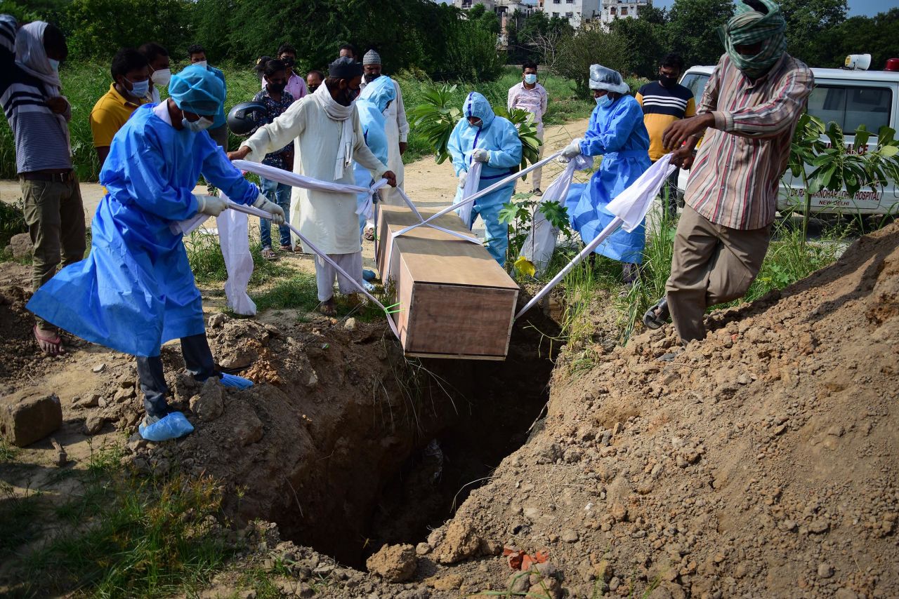 Relatives wearing personal protective equipment (PPE) as a precaution lower the body of a COVID-19 victim for burial at a graveyard in New Delhi, India. 