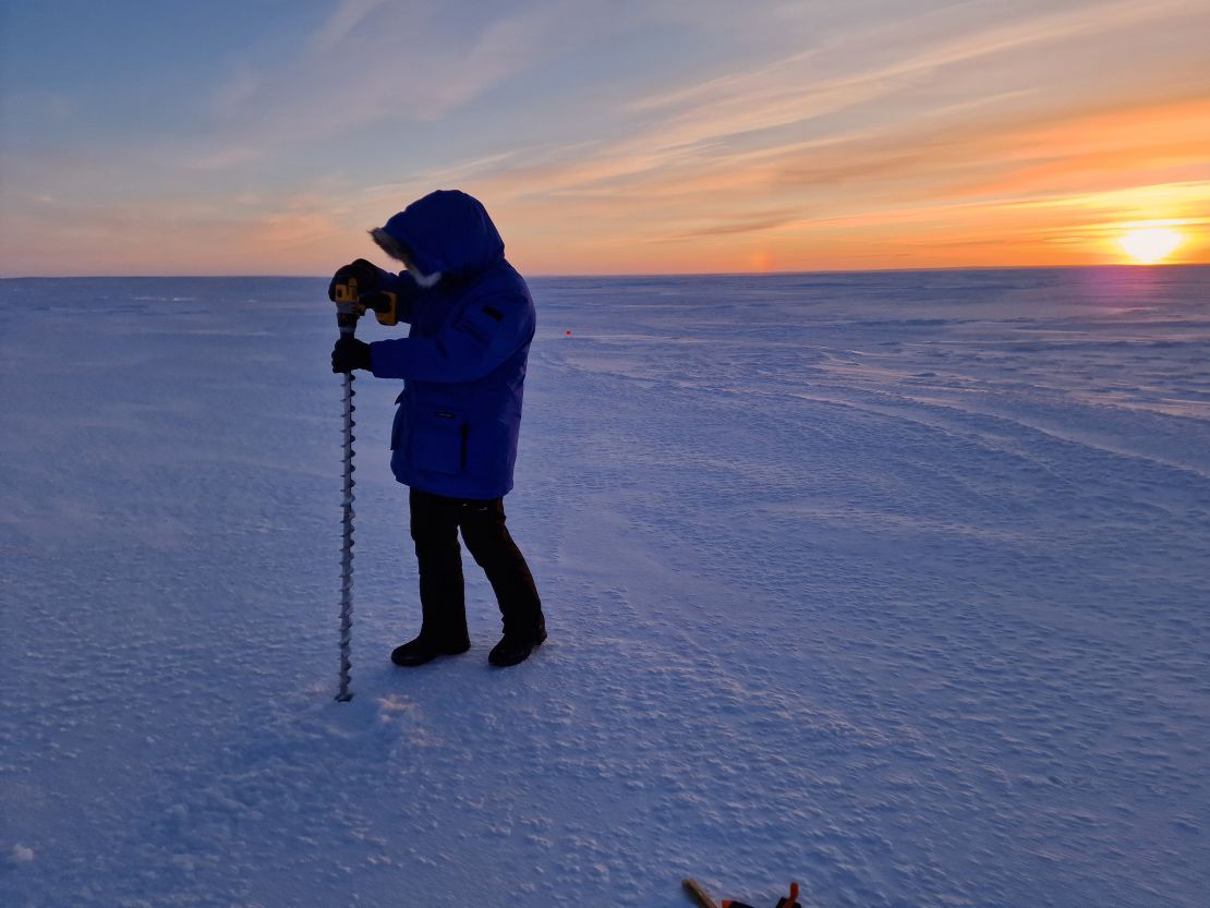 A member of the Real Ice team takes measurements on the sea ice in Cambridge Bay in January 2024.