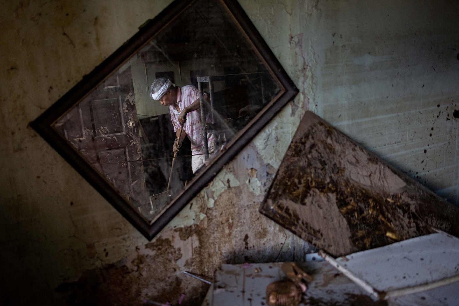 Eusebio Cuyos is reflected in a mirror on Wednesday, November 5, as he sweeps mud out of his home, which was flooded by <a href="index.php?page=&url=https%3A%2F%2Fwww.cnn.com%2F2025%2F11%2F04%2Fasia%2Ftyphoon-kalmaegi-deaths-philippines-cebu-intl">Typhoon Kalmaegi</a> in Cebu City, Philippines.