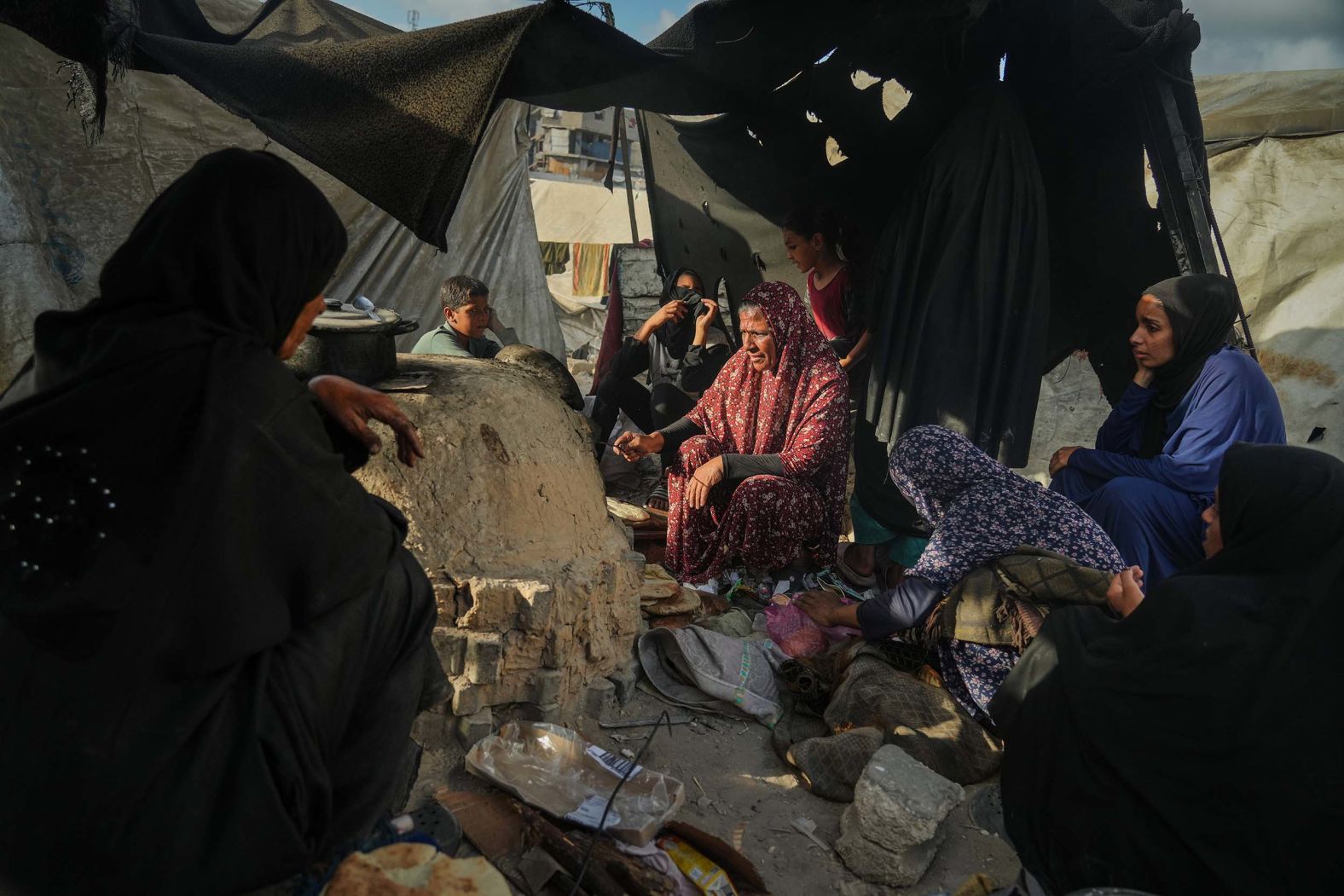 Women bake bread in a clay oven, using plastic for fire, at a shelter for displaced Palestinians in Khan Younis, Gaza, on Sunday, October 5.