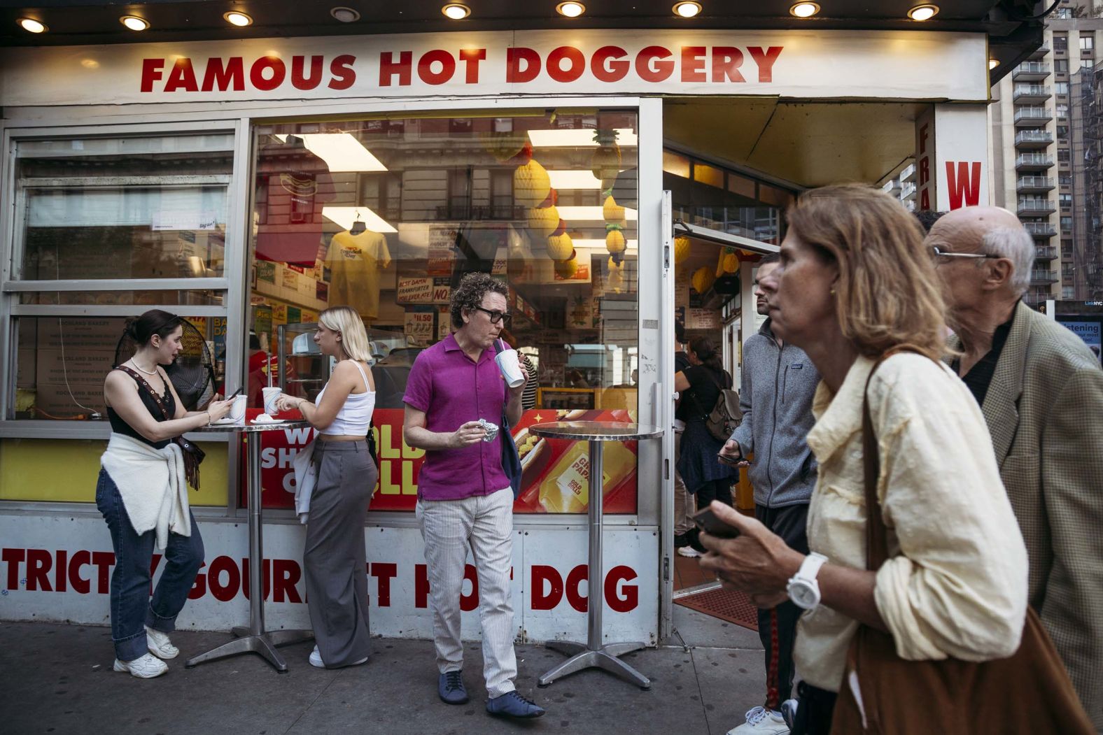 Customers eat hot dogs outside Gray's Papaya in New York on Friday, September 26. The bustling business isn’t just an iconic New York City bastion for cheap eats — it also moonlights as <a href="index.php?page=&url=https%3A%2F%2Fwww.cnn.com%2F2025%2F09%2F30%2Feconomy%2Fus-hot-dog-economic-indicator-recession">an unofficial economic indicator</a>. When hot dog sales there see a dramatic pickup, it’s usually a signal that folks have fallen on harder times, owner Rachael Gray told CNN.