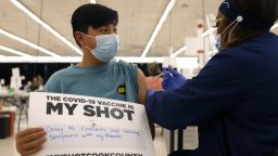 FILE - Lucas Kittikamron-Mora, 13, holds a sign in support of COVID-19 vaccinations as he receives his first Pfizer vaccination at the Cook County Public Health Department, May 13, 2021 in Des Plaines, Ill. The U.S. is expanding COVID-19 boosters as it confronts the omicron surge, with the Food and Drug Administration allowing extra Pfizer shots for children as young as 12. Boosters already are recommended for everyone 16 and older, and federal regulators on Monday, Jan. 3, 2022 decided they're also warranted for 12- to 15-year-olds once enough time has passed since their last dose. (AP Photo/Shafkat Anowar, file)
