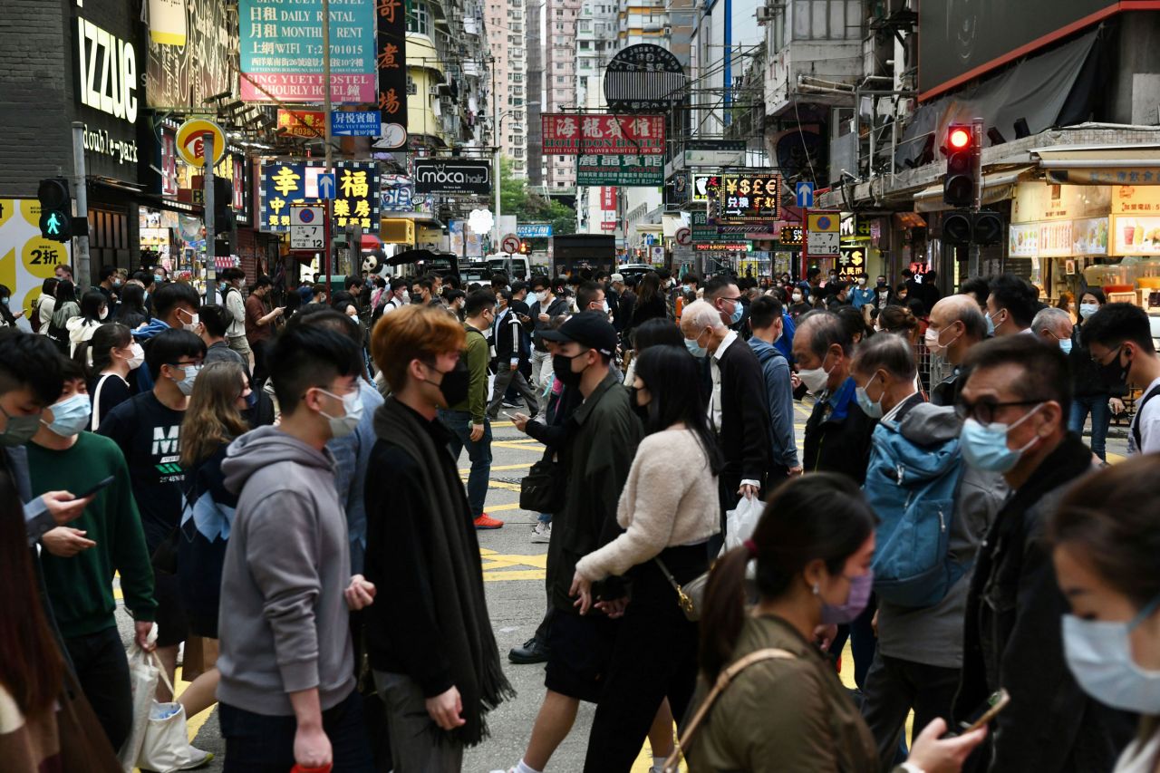 People wearing face masks cross a street in the densely populated Mong Kok district of Hong Kong on December 22, 2021.