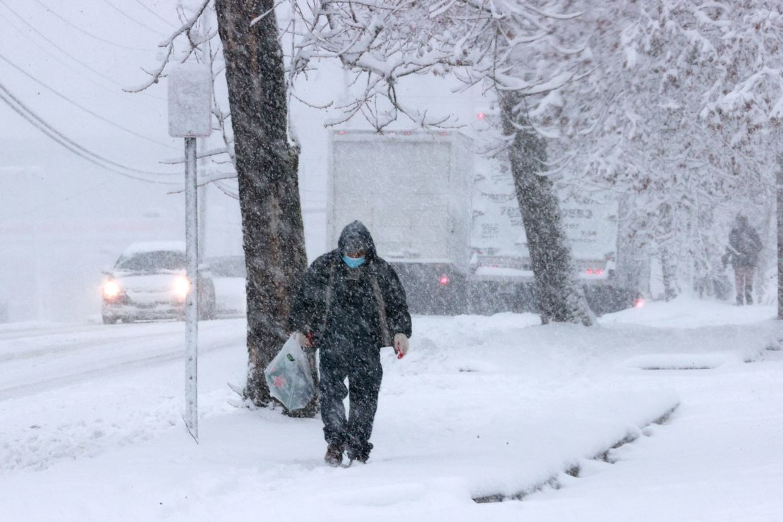 A person walks along the sidewalk in Alexandria, Virginia, as a winter snow storm hits the area Monday.