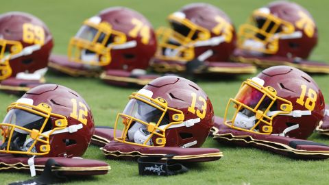 Team football helmets are lined up before practice during the Washington Football Team's training camp. 
