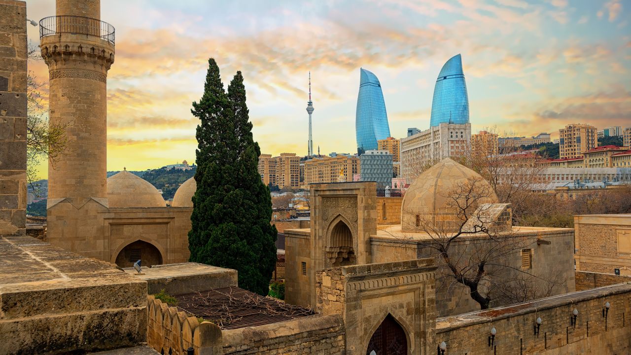 Baku city, Azerbaijan, view of the historical mosques and the walls of Shirvanshahs palace in the Old town and modern glass Flower Towers skyscrapers.