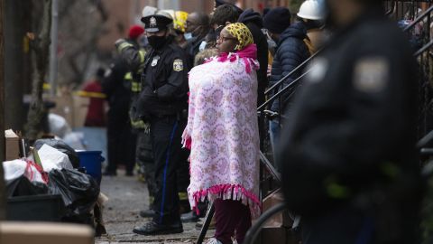 Bystanders watch as the firefighters work at the scene of a deadly row house fire in Philadelphia on Wednesday.