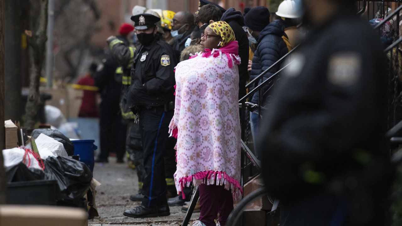 Bystanders watch as firefighters work at the scene of a deadly row house fire in Philadelphia on Wednesday.