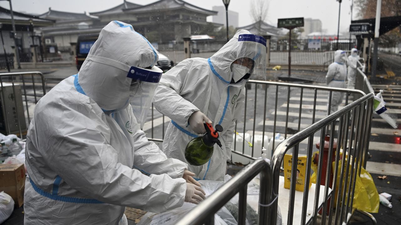 Workers disinfect packed vegetables at a residential area under quarantine in Xi'an, China, on December 25, 2021.