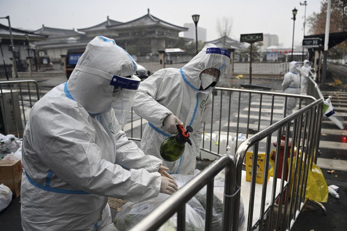 Workers disinfect packed vegetables at a residential area under quarantine in Xi'an, China, on December 25, 2021. 