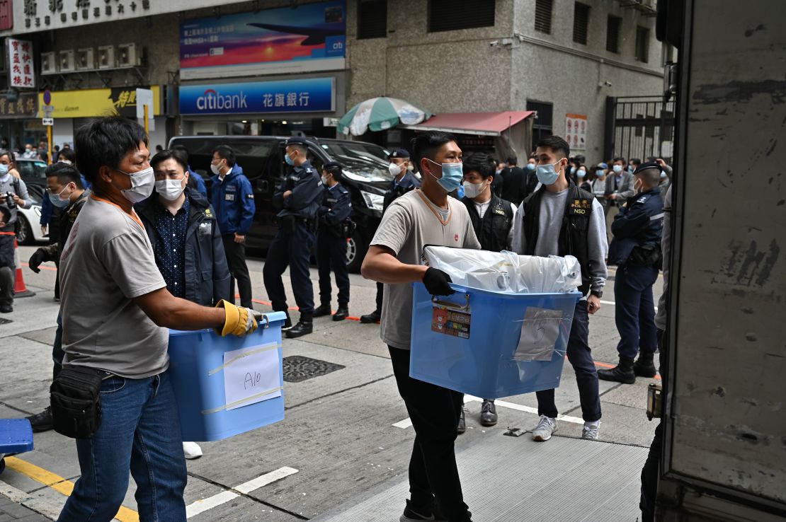 Police officers carry news material and evidence in blue plastic boxes after searching the office of Stand News.
