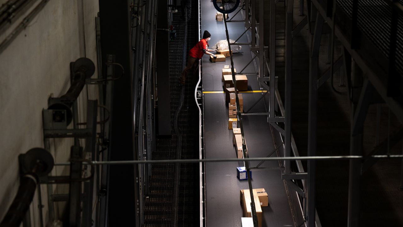 An employee removes packages from a moving conveyor belt in a loading area of the UPS Centennial Ground Hub on December 6, 2021 in Louisville, Kentucky.