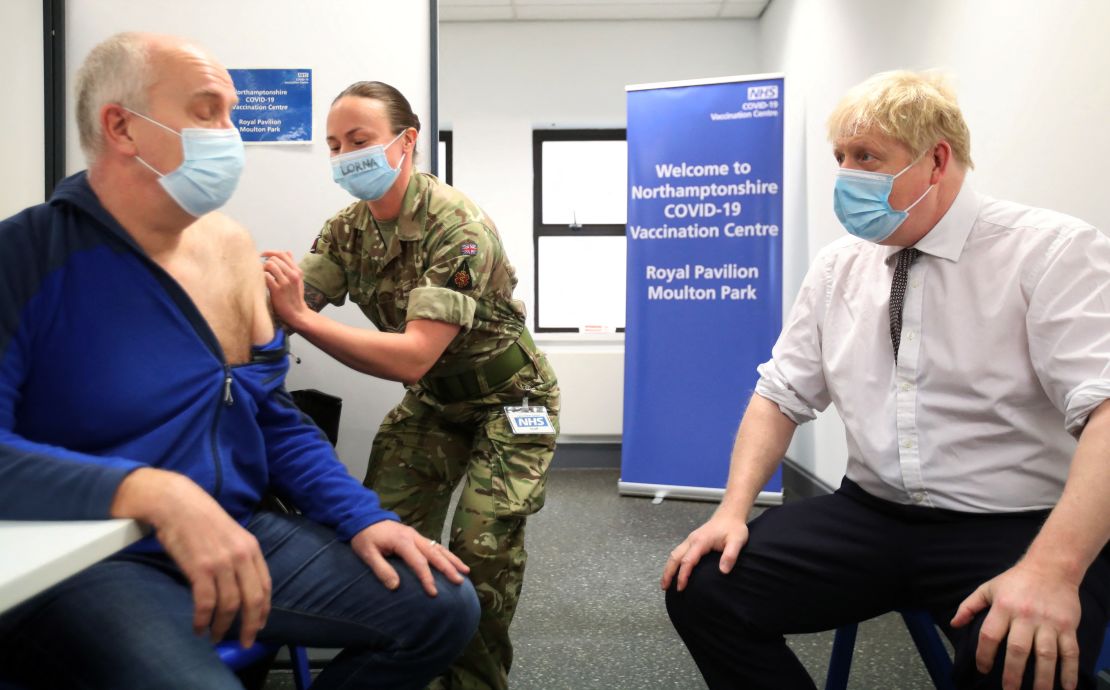 Britain's PM Boris Johnson looks on while Gordon Halfacre receives a vaccine from Cpl. Lorna MacDonald on January 6, 2022 in Northampton, England.