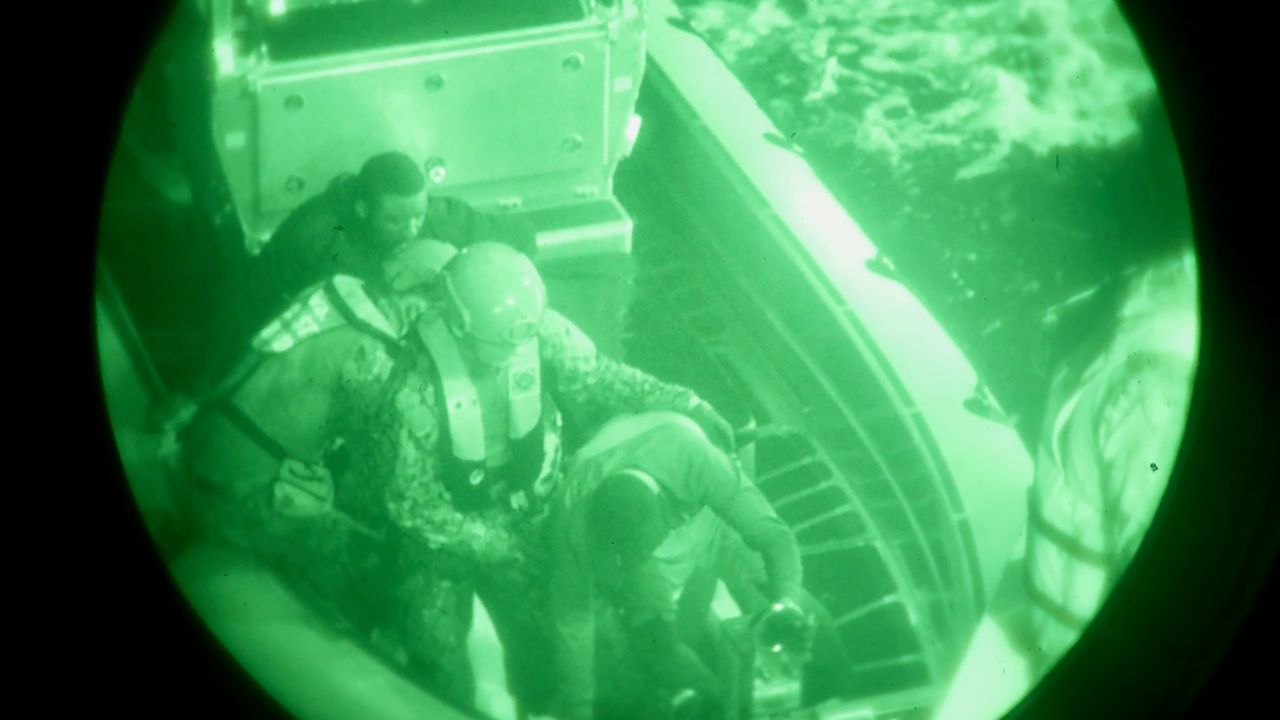 The crew of the USCGC Glen Harris help rescued migrants transfer from their small boat to the cutter in the Atlantic Ocean.