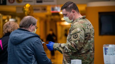 A soldier helps welcome visitors in the lobby handing out new masks and visitor stickers at UMass Memorial Medical Center in Worcester, Massachusetts on December 30, 2021.