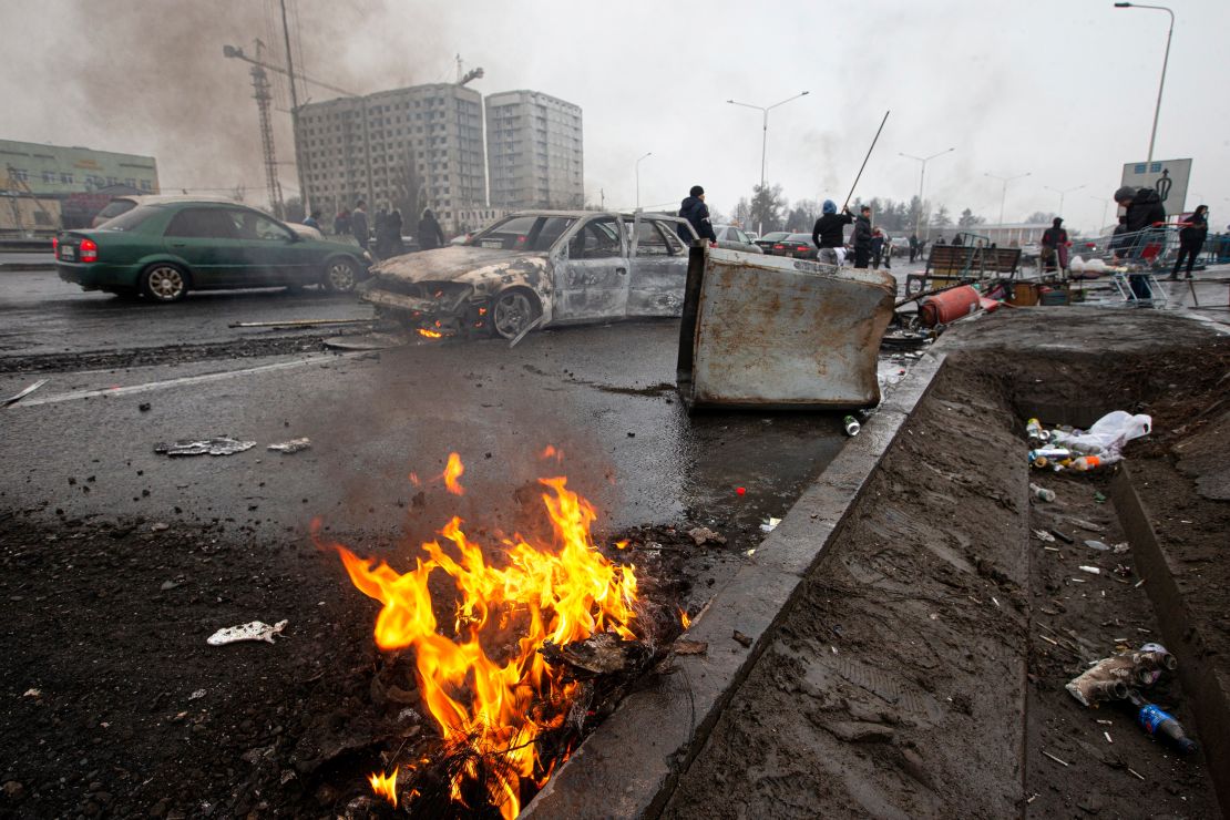 People walk past cars that were burned after clashes, on a street in Almaty, Kazakhstan on Friday, January 7.