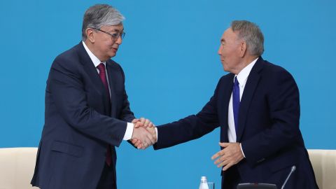 Kazakhstan's President Kassym-Jomart Tokayev (L) and former president Nursultan Nazarbaev shake hands at a party congress in 2019.
