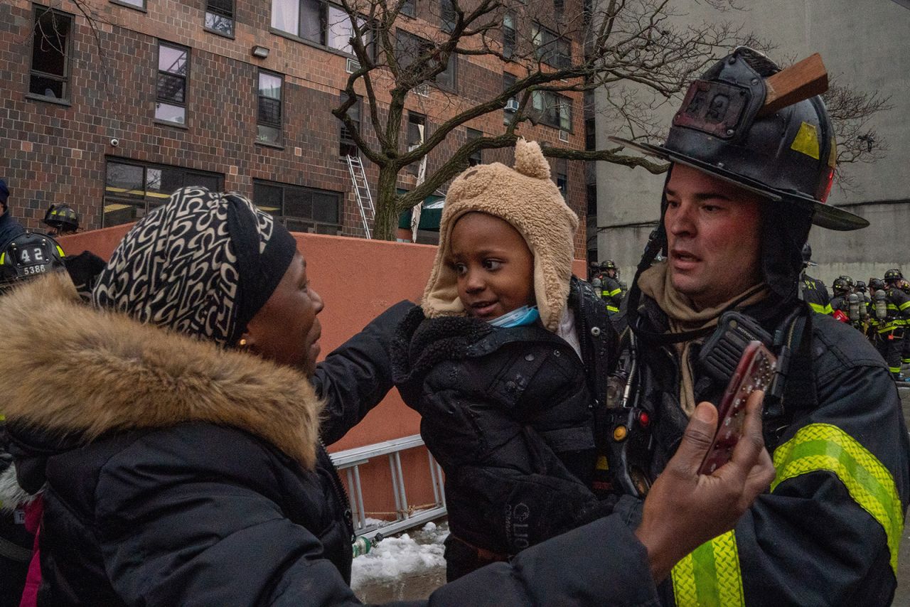 A child is returned to their mother by a firefighter at the scene of the fire. 