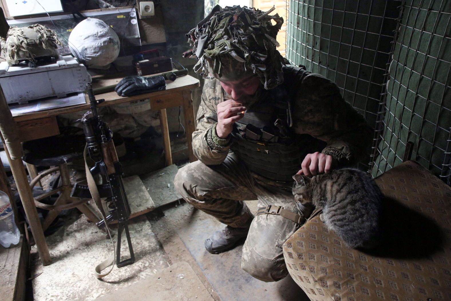 A Ukrainian Military Forces servicemen strokes a cat in a trench at the front line with Russia-backed separatists near to Avdiivka, southeastern Ukraine, on January 9.