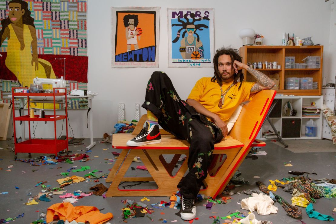 Artist Michael C. Thorpe poses in front of two basketball-themed quilted works. 