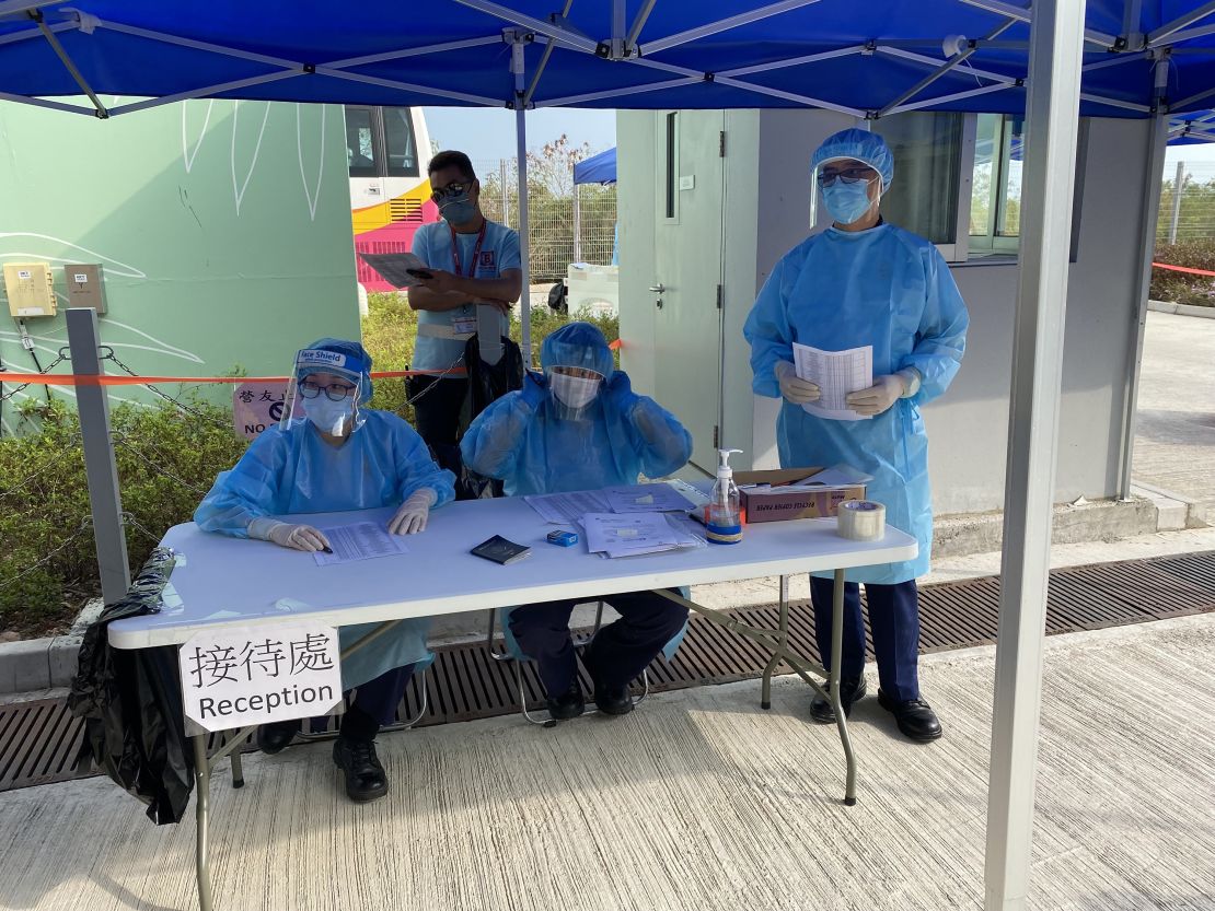 Workers dressed in full protective gear sit behind a reception desk at Penny's Bay.