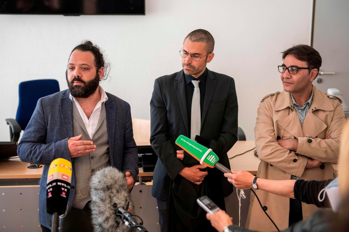 Attorney Patrick Kroker, center, and co-plaintiffs Wassim Mukdad, left, and Hussein Ghrer, right, answer journalists' questions outside the courtroom in Koblenz, Germany, at the start of the trial in April 2020.