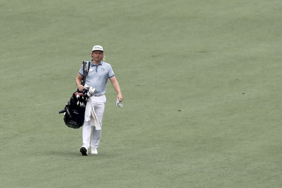 Smith carries his own golf bag as his caddie cleans the fairway bunker on the second hole during the third round of the Masters in 2021.