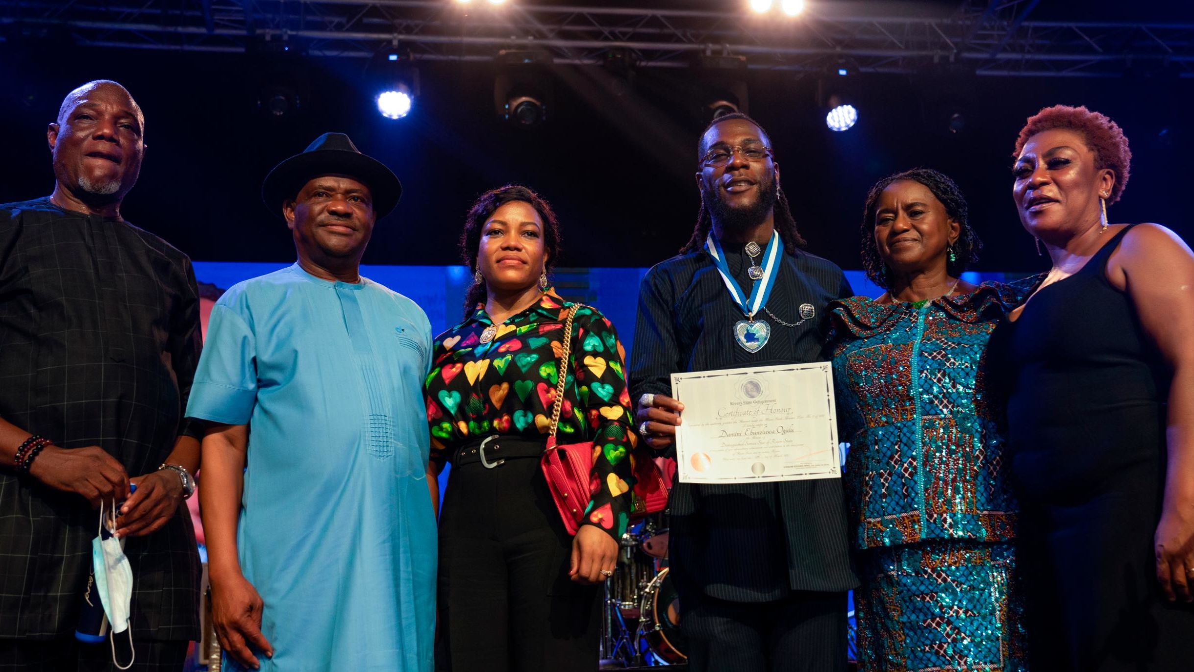 Burna Boy, joined by his father (far left) and mother (far right) received a proclamation from the governor of Rivers State, Nigeria, Ezenwo Nyesom Wike (second from left).