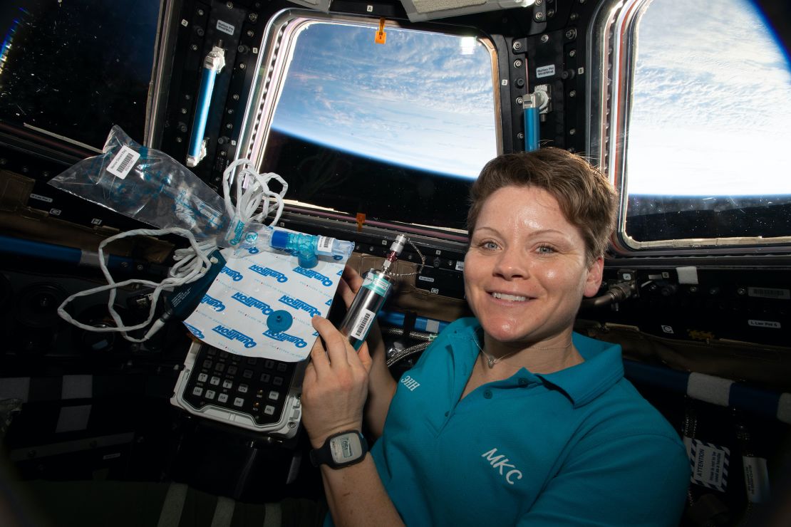 NASA astronaut Anne McClain is shown holding biomedical gear for MARROW on the International Space Station.