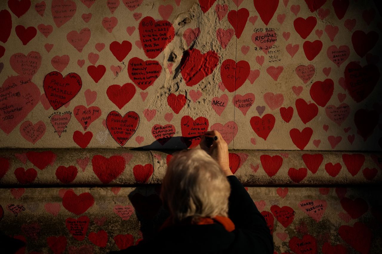 A woman writes a tribute message at the National Covid Memorial Wall in London on Wednesday, January 12.