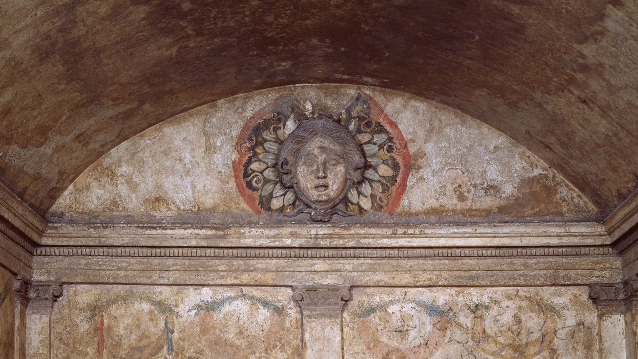 In one tomb, a gorgon watches over the dead.