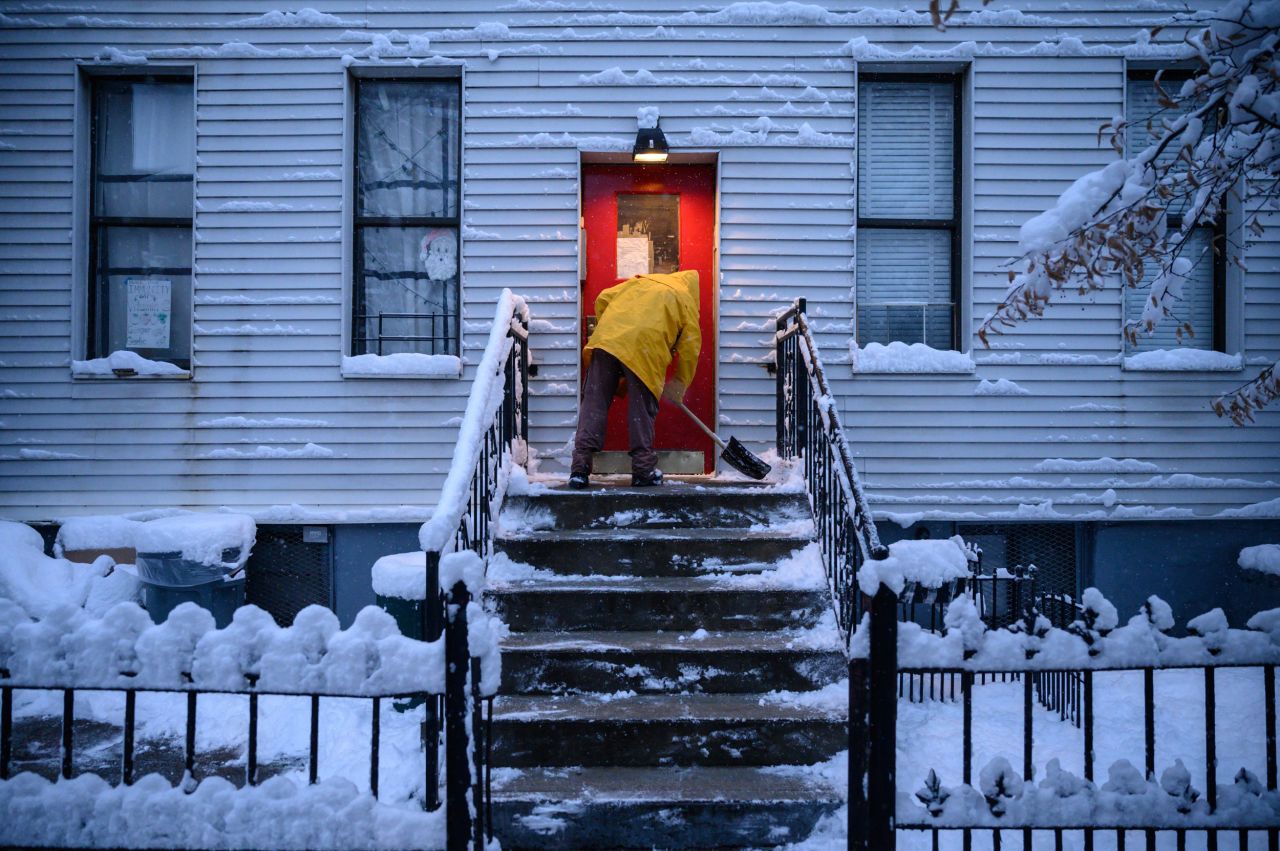 A man shovels snow from a doorway in Brooklyn, New York, during the first snowstorm of the season on Friday, January 7.