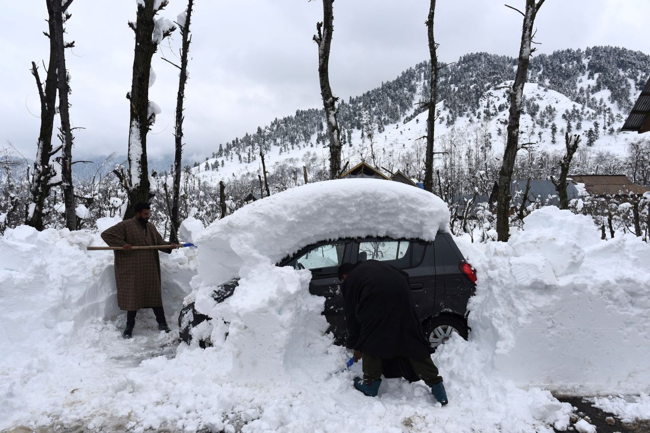 People clear snow from a vehicle in Kulgam, India, on Monday, January 10.