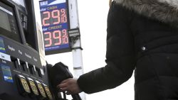 A woman grabs the handle of a gas pump to fill her automobile in the New York City borough of Queens, NY, January 13.