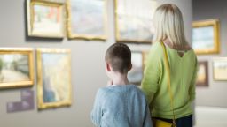 A parent and child look at artwork in a museum.  