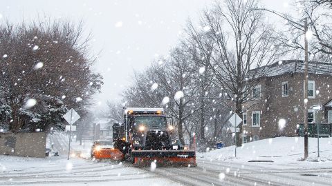 An Iowa City snow plow driver scrapes up slush along Dodge Street as snow falls during a winter storm warning, on January 14, 2022, in Iowa City, Iowa. 