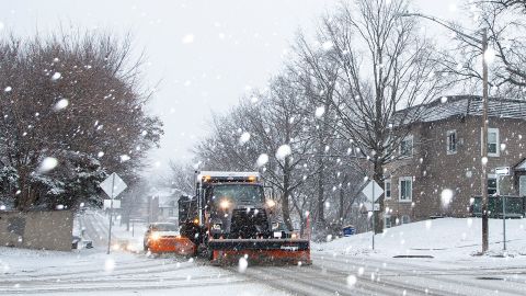 An Iowa City snow plow driver scrapes up slush along Dodge Street as snow falls during a winter storm warning, on January 14, 2022, in Iowa City, Iowa.