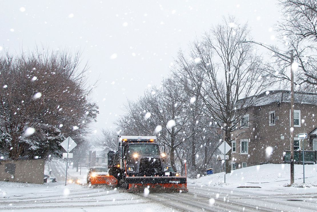 An Iowa City snow plow driver scrapes up slush along Dodge Street as snow falls during a winter storm warning, on January 14, 2022, in Iowa City, Iowa. 