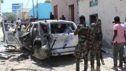 Government soldiers look at the scene of suicide bomb attack in Mogadishu on January 16, 2022. Somali government spokesman Mohamed Ibrahim Moalimu was wounded after a suicide bomber targeted a vehicle he was riding, police and witnesses said.