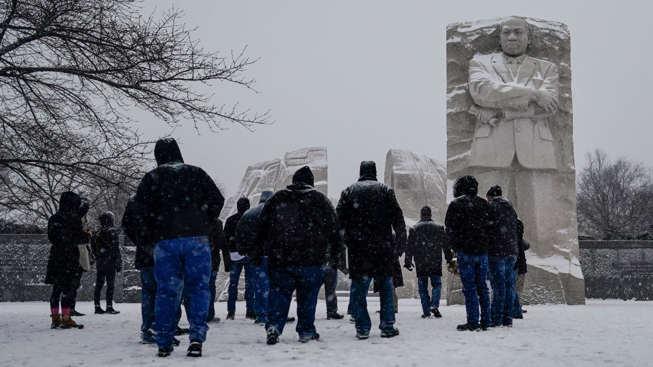 Visitors visit the Martin Luther King, Jr. Memorial as snow falls Sunday in Washington, DC.