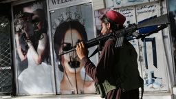 A Taliban fighter walks past a beauty salon with images of women defaced using spray paint in Shar-e-Naw in Kabul on August 18, 2021. (Photo by Wakil KOHSAR / AFP) (Photo by WAKIL KOHSAR/AFP via Getty Images)