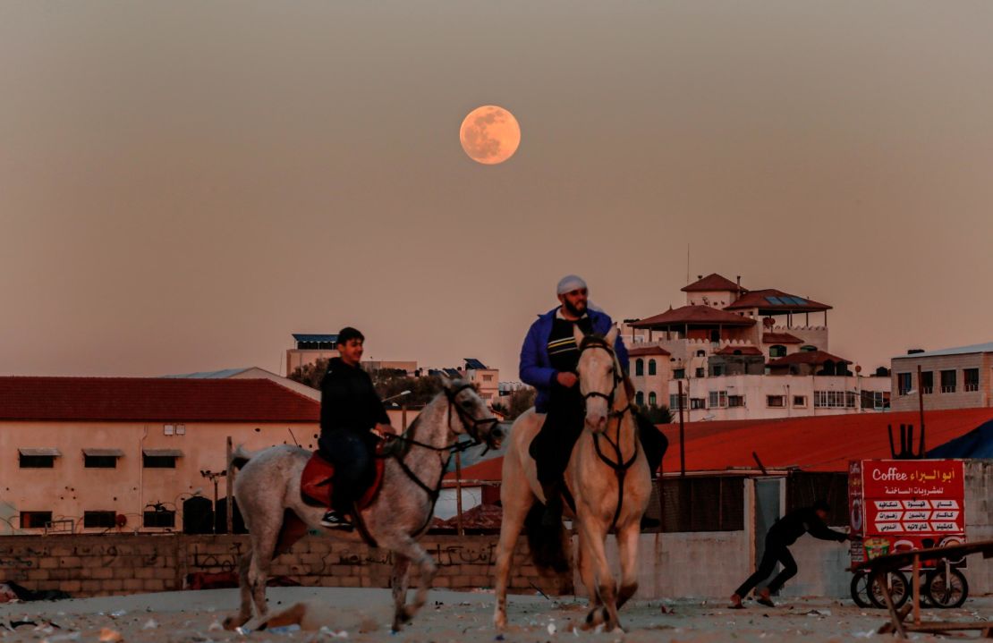 Palestinians ride horses in Gaza beach as the full wolf moon rises over Gaza City on January 17.
