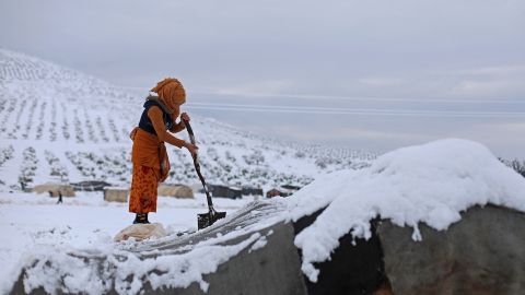 A woman shovels snow off her tent at a camp for internally displaced people in Raju, Syria.
