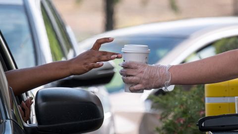 A Starbucks employee hands a customer an order from a drive-thru window in April 2020.